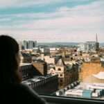 woman looks out over glasgow skyline from office tower